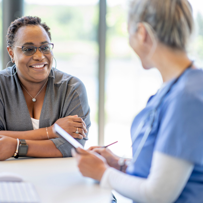 A middle-aged Black female patient having a conversation with her her female Caucasian healthcare provider.